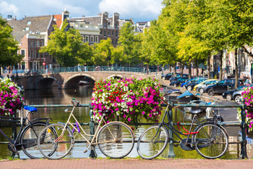 Bicycles on a bridge over the canals of Amsterdam - obrazy, fototapety, plakaty