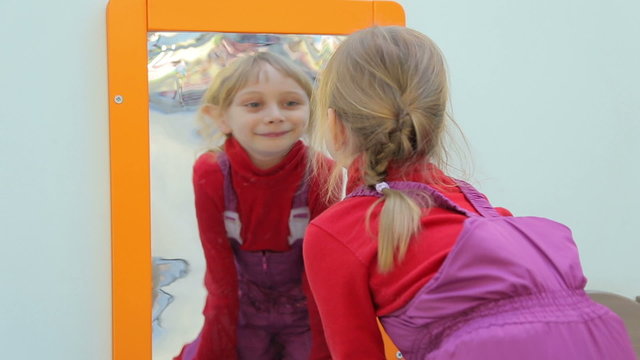 Girl looking at herself in a distorting mirror and smiling