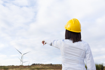 Back view of a female engineer pointing to windmills