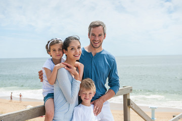 Fototapeta premium happy family standing on a wood pontoon in front of the sea in
