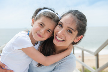 beautiful mom and her daugther at seaside smiling at camera