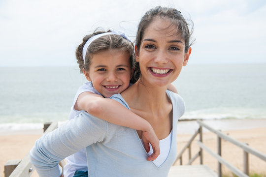 beautiful mom and her daugther at seaside smiling at camera