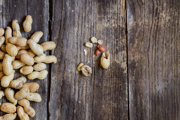 whole organic peanuts cracked on wooden table - top view