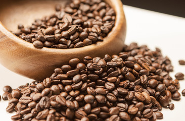 Heap of Brown Roasted Coffee Beans in Wooden Bowl on White Surfa