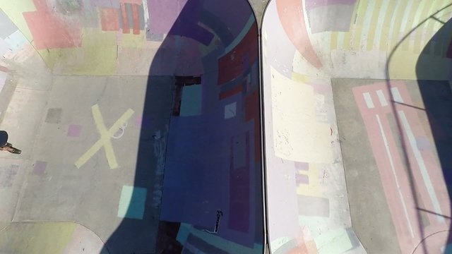 Overhead aerial of roller blade rider jumping from ramp to ramp