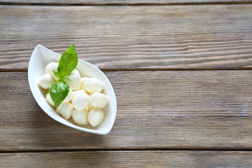 Balls of mozzarella in white bowl and  basil