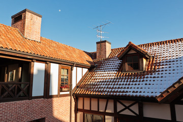 Tiled roof of a house with chimney, antenna and snow