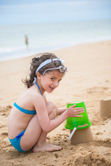 a little girl playing in the sand at the sea