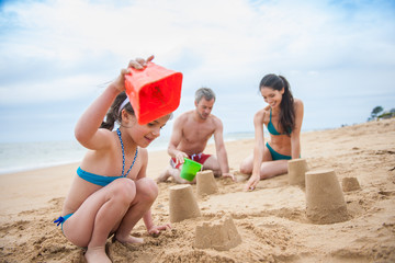 A young couple is playing at the beach with their daughter