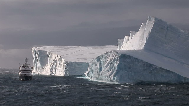 Cruise ship in front of huge icebergs in Antarctica