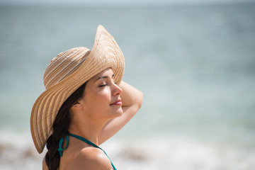 Portrait of a beautiful girl with a big hat at the beach