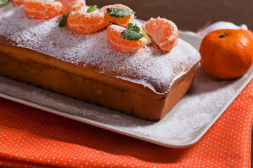 Homemade cake with tangerines and mint on a wooden background