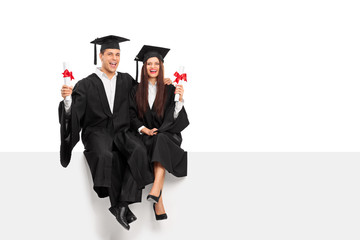 Couple holding diplomas and celebrating graduation