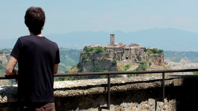 man looks at a medieval village ( civita di bagnoreggio) " the city that dies "