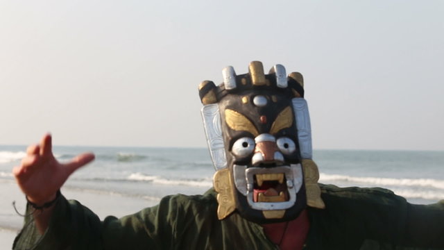 man in the mask is frightening somebody and is waving on the bea