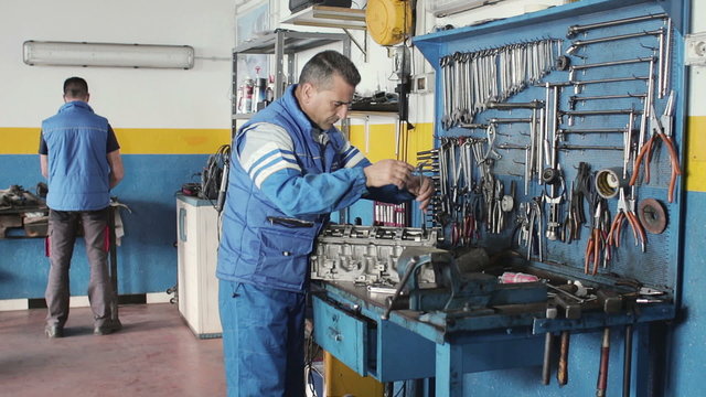 Auto mechanic repairing a car with socket wrench - dolly
