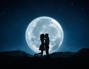 Loving couple kissing against the full moon