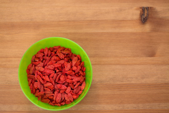 dried goji berries in green bowl on wooden table