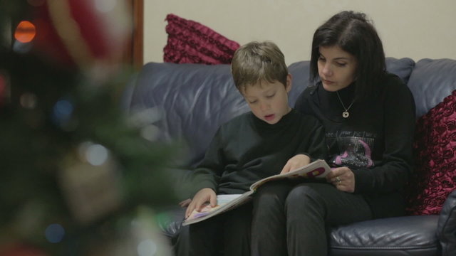 Mom and young son reading a book of fairy tales - during the Christmas season