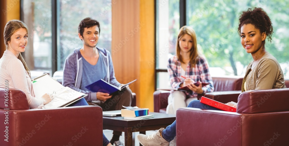 Aufkleber students sitting on couch revising and smiling at camera