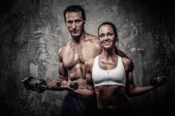 Fototapeta na wymiar Athletic man and woman with a dumbbells