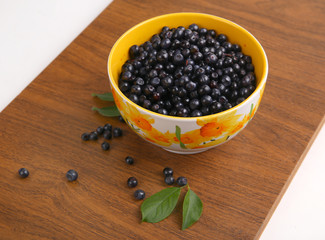 blueberries with leaf in bowl, cup, plate on wooden background