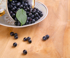 blueberries with leaf in bowl, cup on wooden background