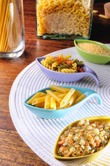 uncooked pasta in ceramic containers on a white tablecloth