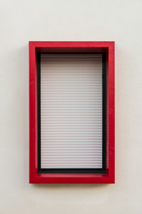 Geschlossener Rollladen und rote Fenstereinfassung aus Holz