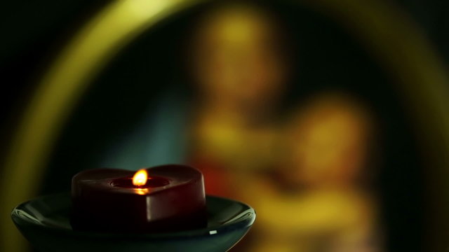 candle in the shape of heart on background a painting with madonna and christ