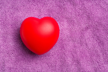 Red heart on purple cloth background