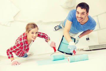 smiling couple painting wall at home