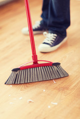 close up of male brooming wooden floor