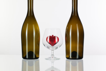 Two bottles and red heart inside a glass of cognac