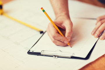 close up of male hands writing in clipboard