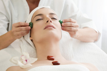 Obraz na płótnie Canvas Spa salon: Young Beautiful Woman Having Facial Massage with Ston