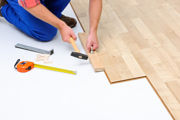 Fototapeta na wymiar Man laying laminate flooring