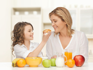 happy mother and daughter eating breakfast