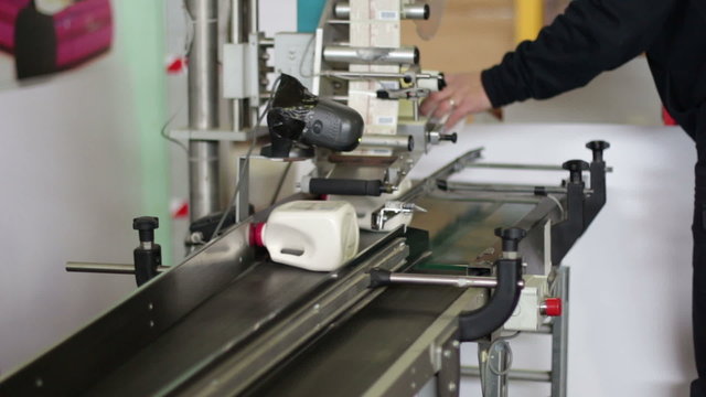 worker puts bottles in the machine to label them