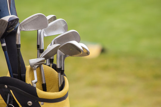 set of golf clubs over green field background