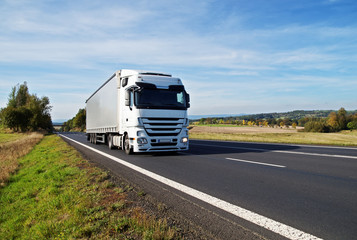 White truck travels on the asphalt road in the countryside