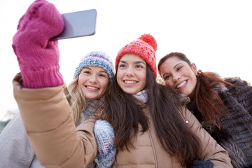 happy teenage girls taking selfie with smartphone