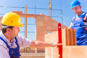 Zwei Handwerker kontrollieren Wände auf einer Baustelle