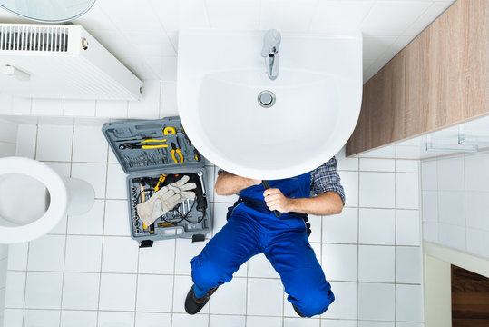 Plumber Repairing Sink In Bathroom