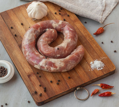 Ring of raw sausage on a cutting board with pepper