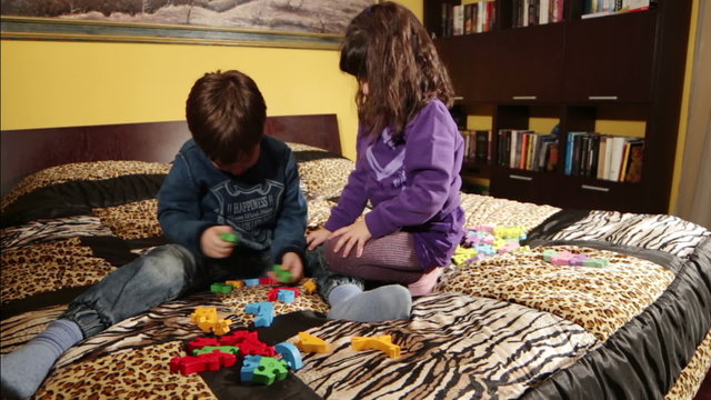 little girl kiss her cousin while playing with puzzles