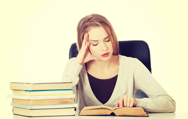 Casual student woman sitting by stack of books.