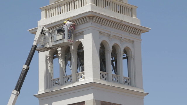 masons do maintenance work of a church with a boom lift - crane - worker