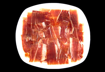 Plate of spanish serrano ham on black background.