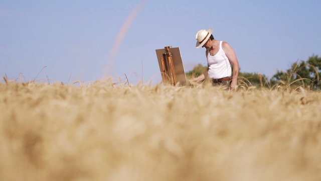 painter in the middle of a wheat field paints a beautiful landscape, canvas